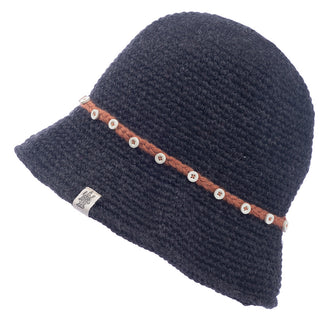 The Emily Sun Hat is a black woven sun hat with a brown braided band around the base, adorned with small white beads. Handmade and crafted from 100% wool, it features a tag with an indistinguishable design attached to the hat.