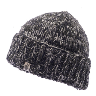 The Marbled Rib Fold Beanie is displayed, featuring shades of gray and black with a fold-up brim. This hand-knit hat, crafted in Nepal, includes a textile tag with a small logo on the folded part. It boasts a consistent knitting pattern with a heathered texture and has a snug sherpa lining for enhanced warmth.