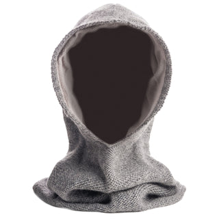 The Roll Hood is a gray knit wool hood, handcrafted in Nepal, shown upright on a white background. Its hollow center and absence of face or head highlight its form and unique handmade quality.